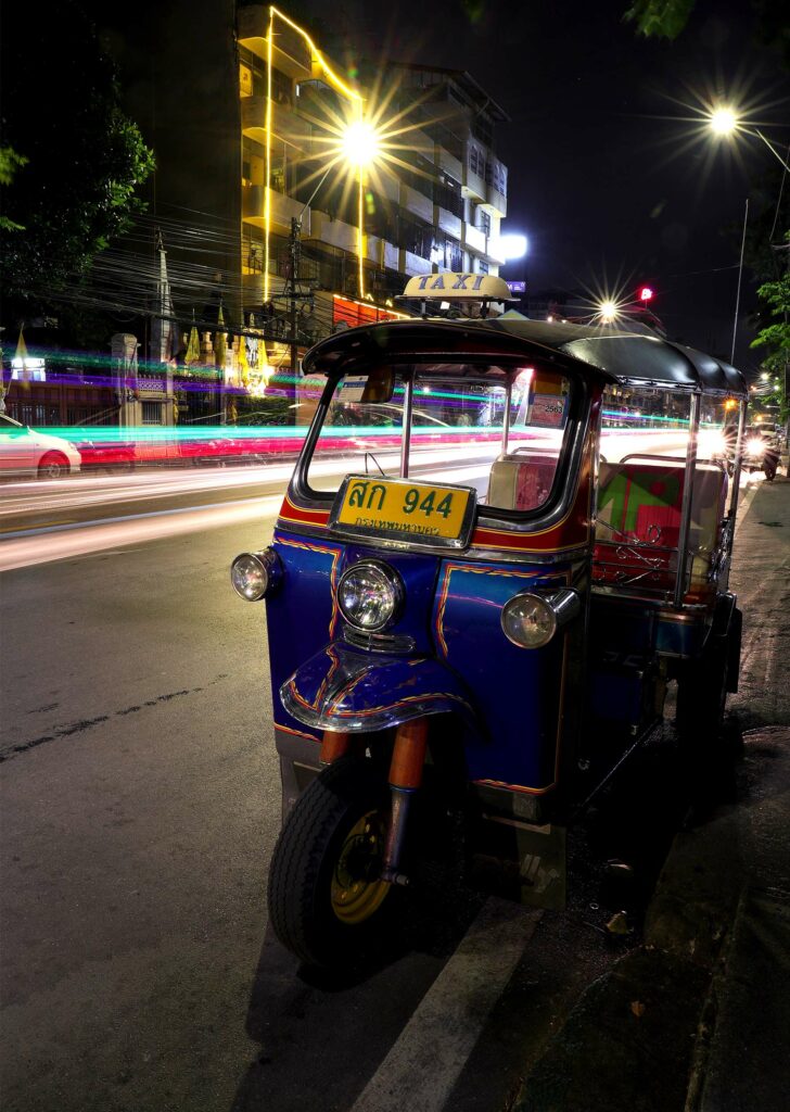 Long exposure night time photograph of a tuk tuk in Bangkok.